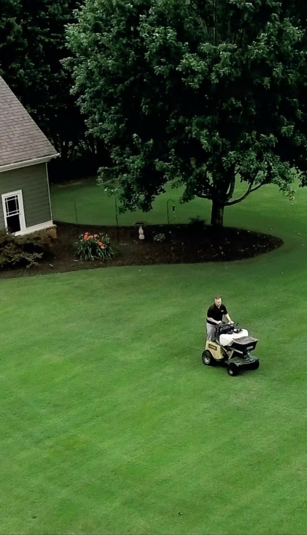 Aerial view of a Show Turf team member mowing a large, healthy green lawn in North Georgia